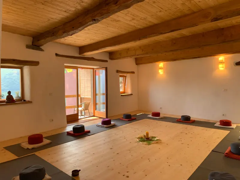 Heller Meditationsraum mit Holzbalken und Kissen