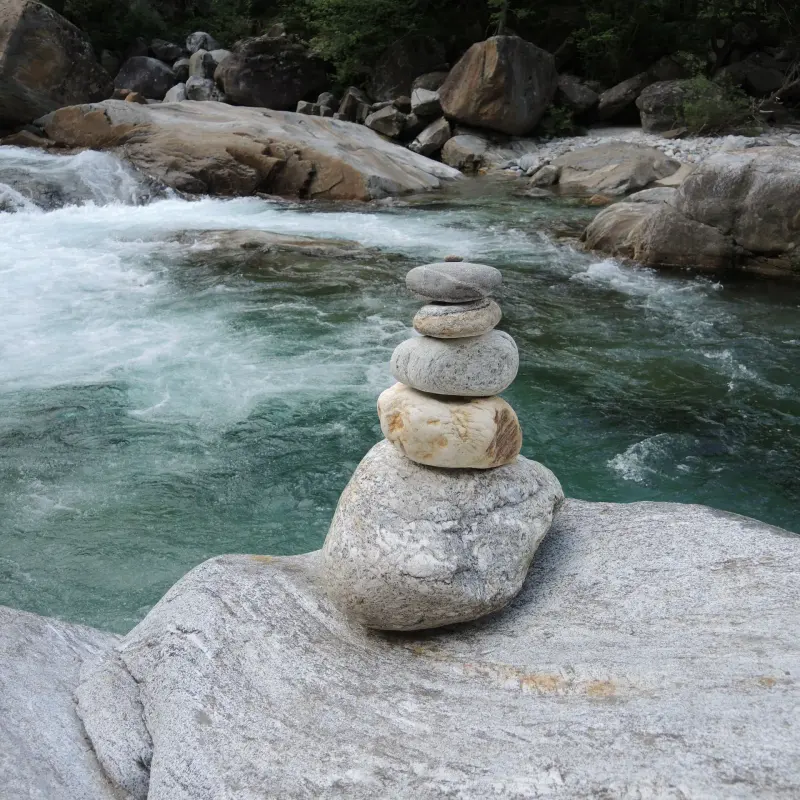 Aufgeschichtete Steine auf einem Felsen am Gebirgsfluss